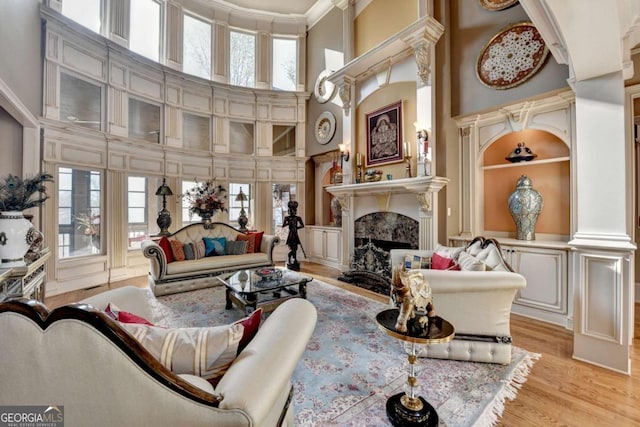 2279 Weeping Oak Dr, Braselton, GA 30517 - living area with a fireplace, plenty of natural light, a towering ceiling, light wood-style flooring, and built in shelves