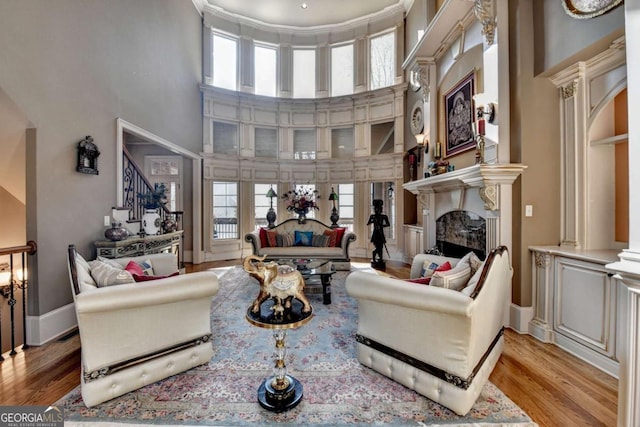 2279 Weeping Oak Dr, Braselton, GA 30517 - living room with a high ceiling, a fireplace, light wood finished floors, stairs, and baseboards