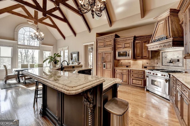 2279 Weeping Oak Dr, Braselton, GA 30517 - kitchen featuring a chandelier, built in appliances, high vaulted ceiling, premium range hood, and a kitchen breakfast bar