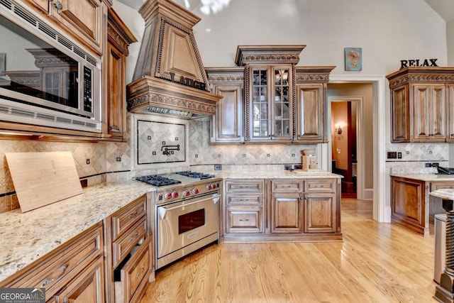 2279 Weeping Oak Dr, Braselton, GA 30517 - kitchen featuring appliances with stainless steel finishes, backsplash, light wood finished floors, and light stone countertops