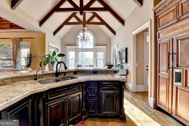 2279 Weeping Oak Dr, Braselton, GA 30517 - kitchen with a sink, light stone counters, beam ceiling, a chandelier, and light wood-style floors