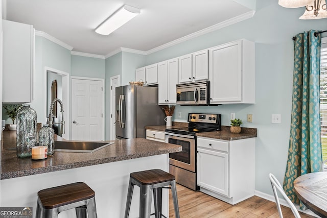 167 Maggies Pt, Dallas, GA 30132 - kitchen featuring appliances with stainless steel finishes, dark countertops, a breakfast bar area, crown molding, and light wood-type flooring