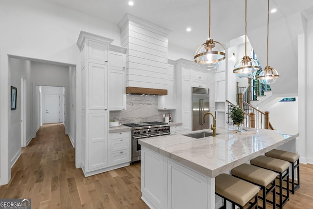 4235 Drew Campground Rd, Alpharetta, GA 30004 - kitchen with high quality appliances, decorative backsplash, white cabinetry, light wood-type flooring, and a kitchen island with sink