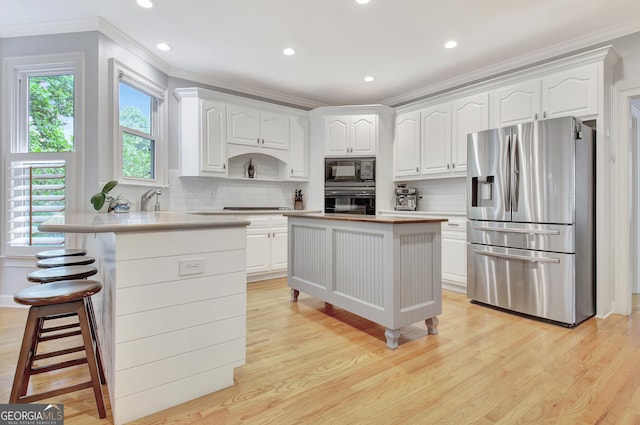 505 Lighthouse Ln, Peachtree City, GA 30269 - kitchen featuring black appliances, crown molding, a kitchen breakfast bar, light wood finished floors, and white cabinetry