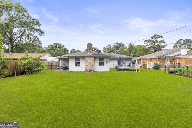 314 Clifton Dr, Port Wentworth, GA 31407 - back of house featuring a trampoline, a fenced backyard, and a chimney