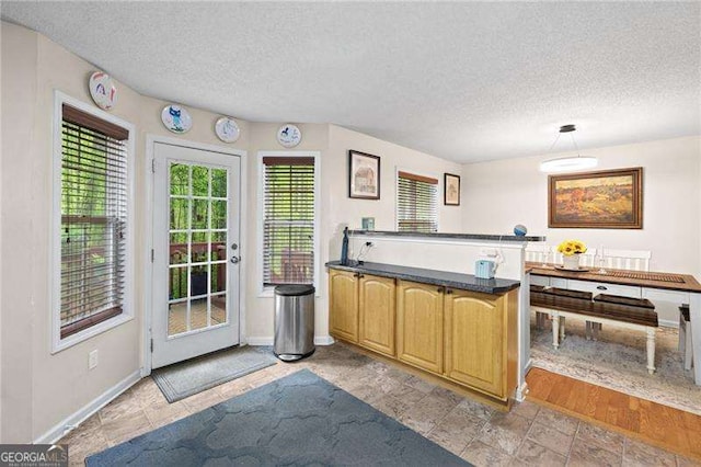 69 Due W Pass, Dallas, GA 30157 - kitchen with a textured ceiling, dark countertops, a peninsula, light stone finish flooring, and hanging light fixtures