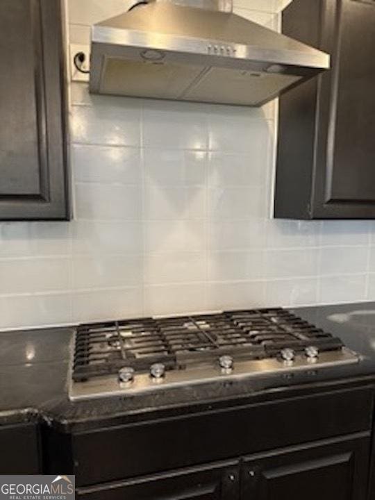 121 Fountain Oak, Villa Rica, GA 30180 - kitchen featuring wall chimney exhaust hood, decorative backsplash, dark countertops, and stainless steel gas stovetop