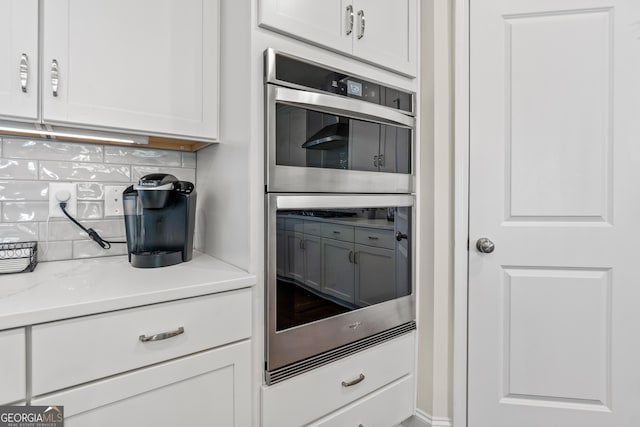 2884 Porches Ln, Dacula, GA 30019 - kitchen with stainless steel double oven, tasteful backsplash, and white cabinetry