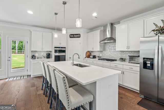 2884 Porches Ln, Dacula, GA 30019 - kitchen featuring appliances with stainless steel finishes, a sink, wall chimney range hood, ornamental molding, and an island with sink