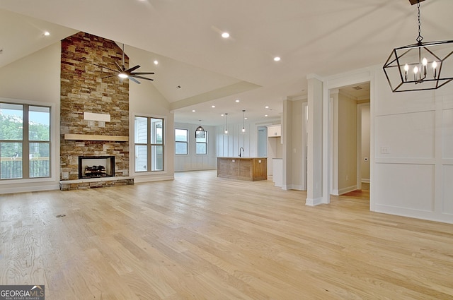 375 Werner Way, Senoia, GA 30276 - unfurnished living room featuring a chandelier, light wood finished floors, a stone fireplace, high vaulted ceiling, and ceiling fan