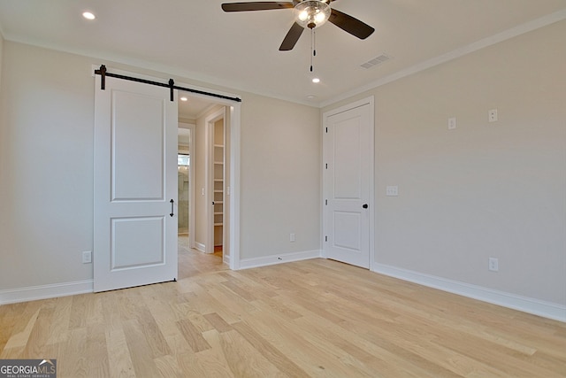 375 Werner Way, Senoia, GA 30276 - unfurnished bedroom with a barn door, light wood-type flooring, ornamental molding, recessed lighting, and a ceiling fan