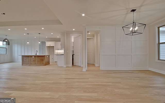 375 Werner Way, Senoia, GA 30276 - kitchen with a decorative wall, open floor plan, light wood-style flooring, a chandelier, and white cabinets
