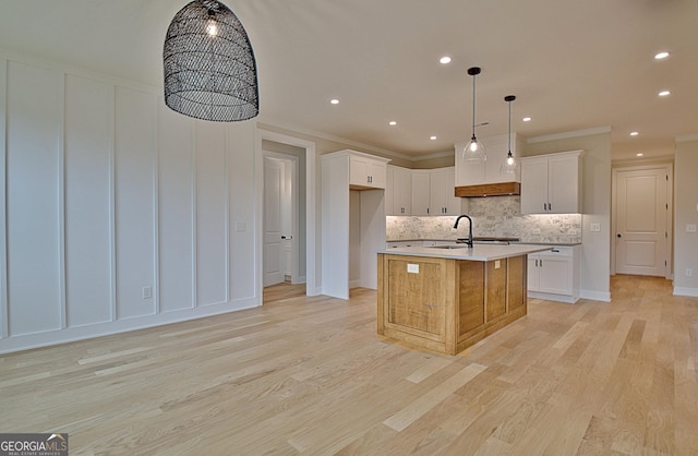 375 Werner Way, Senoia, GA 30276 - kitchen featuring decorative backsplash, light wood-type flooring, light countertops, a kitchen island with sink, and white cabinetry