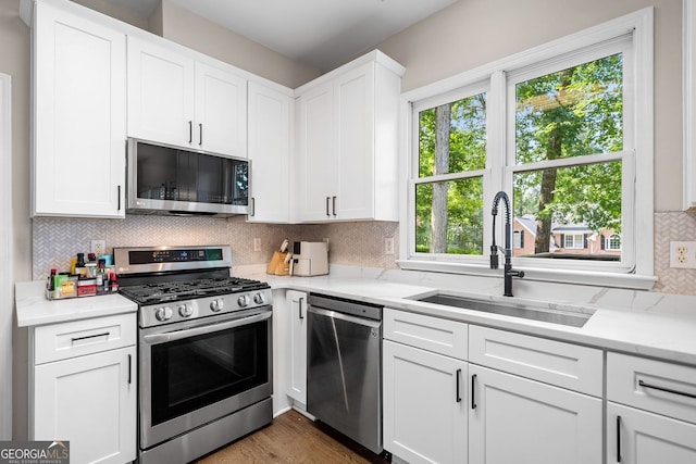 1205 Compass Pointe Xing, Alpharetta, GA 30005 - kitchen with appliances with stainless steel finishes, a sink, decorative backsplash, white cabinetry, and wood finished floors