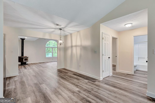 85 Prestigious Pl, Senoia, GA 30276 - unfurnished living room featuring wood finished floors, baseboards, a wood stove, a textured ceiling, and vaulted ceiling