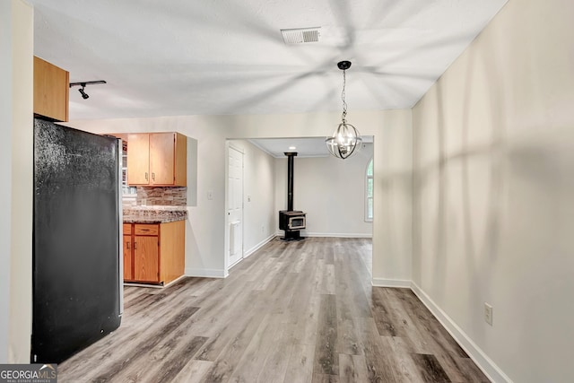 85 Prestigious Pl, Senoia, GA 30276 - unfurnished dining area with light wood-style flooring, a wood stove, and baseboards