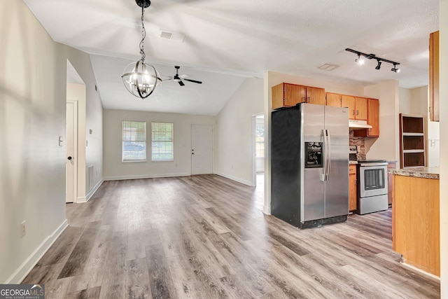 85 Prestigious Pl, Senoia, GA 30276 - kitchen featuring appliances with stainless steel finishes, under cabinet range hood, light wood-style flooring, baseboards, and lofted ceiling