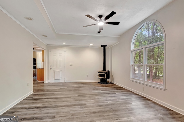 85 Prestigious Pl, Senoia, GA 30276 - unfurnished living room featuring a wood stove, ornamental molding, ceiling fan, wood finished floors, and baseboards