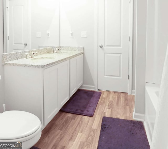 20 Sloane Ct Unit 64, Covington, GA 30016 - bathroom featuring toilet, wood finished floors, double vanity, and a bathtub