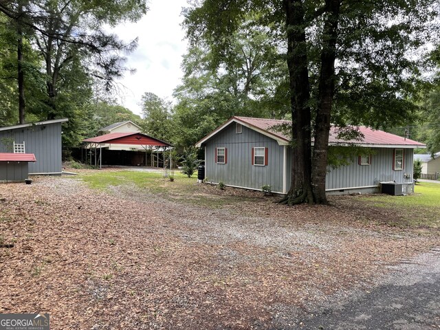 501 Lakeshore Dr, Monticello, GA 31064 - view of side of home with a detached carport, dirt driveway, and central AC unit