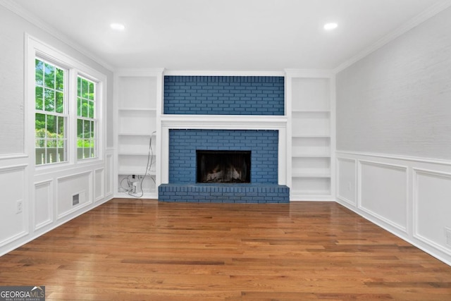 4197 Chadds Xing, Marietta, GA 30062 - unfurnished living room with built in features, wood finished floors, ornamental molding, a brick fireplace, and recessed lighting