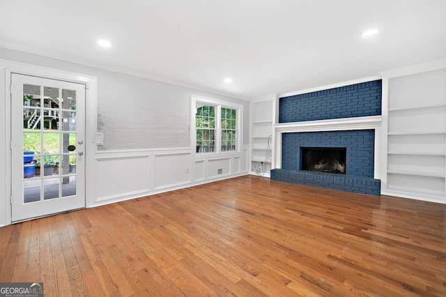4197 Chadds Xing, Marietta, GA 30062 - unfurnished living room with ornamental molding, hardwood / wood-style flooring, a wainscoted wall, built in shelves, and a fireplace