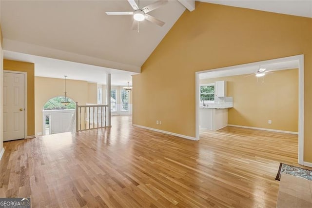 12290 Greenmont Walk, Alpharetta, GA 30009 - unfurnished living room with ceiling fan, high vaulted ceiling, beamed ceiling, light wood finished floors, and baseboards