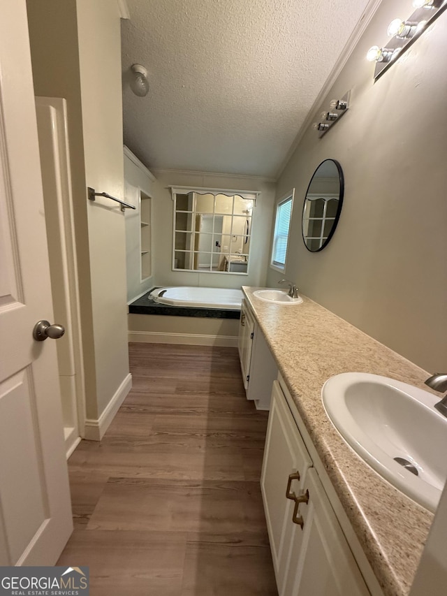 179 Creek Ridge Rd, Claxton, GA 30417 - bathroom featuring a textured ceiling, double vanity, a garden tub, and wood finished floors