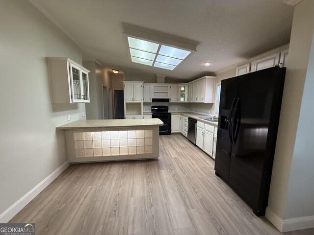 179 Creek Ridge Rd, Claxton, GA 30417 - kitchen featuring black appliances, a peninsula, vaulted ceiling, light countertops, and glass insert cabinets