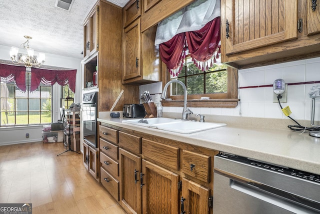 2969 White Rd NE, Conyers, GA 30012 - kitchen with appliances with stainless steel finishes, brown cabinetry, a chandelier, light countertops, and a textured ceiling