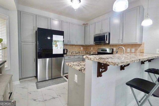 5996 Eagle Tiff Ln, Sugar Hill, GA 30518 - kitchen with stainless steel appliances, a peninsula, light marble finish floors, backsplash, and a kitchen bar
