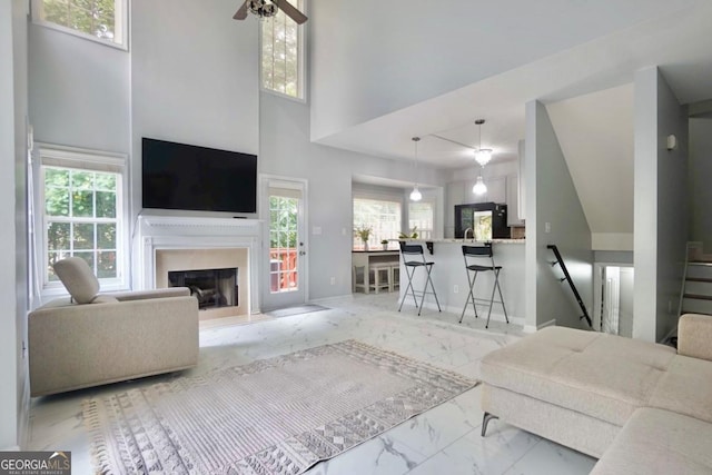5996 Eagle Tiff Ln, Sugar Hill, GA 30518 - living area featuring light marble finish flooring, plenty of natural light, a fireplace, ceiling fan, and a towering ceiling