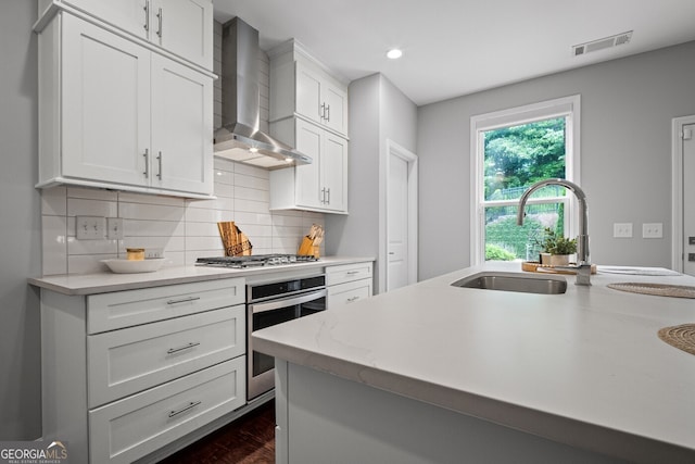 149 Archie Way, Woodstock, GA 30188 - kitchen featuring stainless steel appliances, wall chimney range hood, a sink, tasteful backsplash, and white cabinets