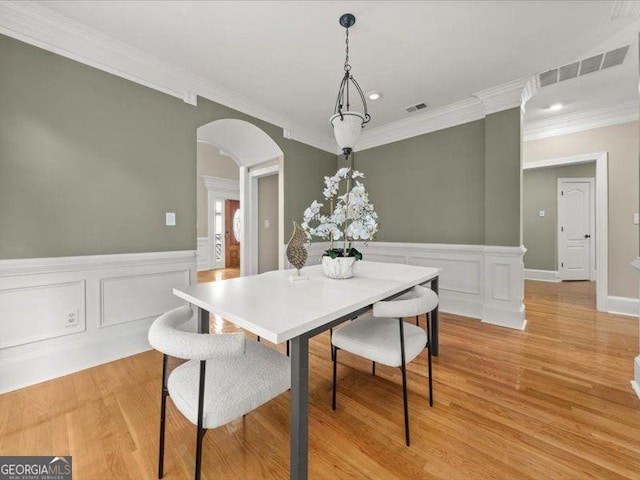 121 Fulton Way SE, Atlanta, GA 30312 - dining room featuring crown molding, arched walkways, light wood-style floors, a decorative wall, and wainscoting