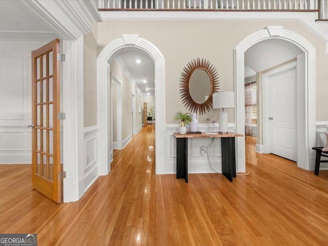 121 Fulton Way SE, Atlanta, GA 30312 - corridor with arched walkways, a decorative wall, light wood-style flooring, crown molding, and a wainscoted wall