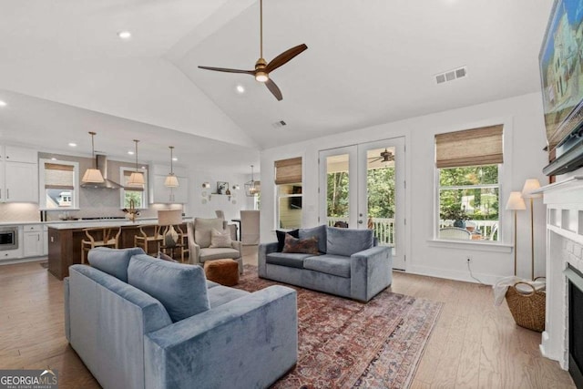 8415 Azure Overlook Trl, Gainesville, GA 30506 - living room featuring a fireplace, light wood finished floors, french doors, ceiling fan, and high vaulted ceiling