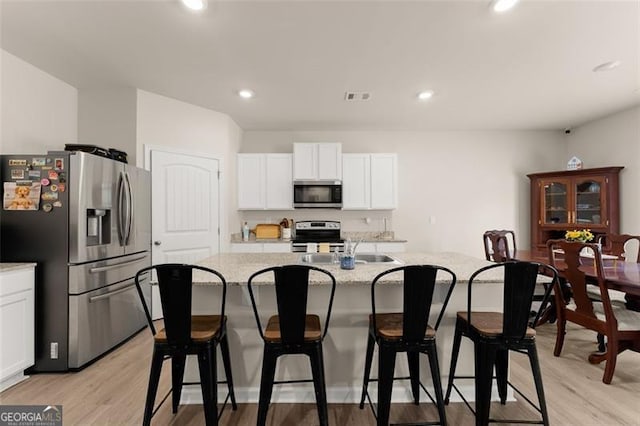 352 Walnut Grove Way, Pendergrass, GA 30567 - kitchen featuring appliances with stainless steel finishes, white cabinets, light wood finished floors, an island with sink, and recessed lighting