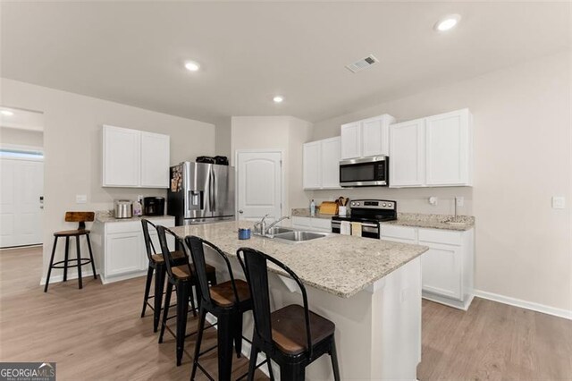 352 Walnut Grove Way, Pendergrass, GA 30567 - kitchen featuring appliances with stainless steel finishes, a sink, a breakfast bar area, a center island with sink, and light wood finished floors