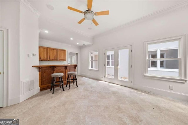 6771 Sunny Brook Ln, Atlanta, GA 30328 - kitchen featuring crown molding, brown cabinetry, a breakfast bar area, french doors, and a peninsula