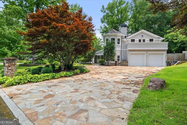 6771 Sunny Brook Ln, Atlanta, GA 30328 - victorian house with a garage, decorative driveway, stucco siding, a chimney, and a front lawn