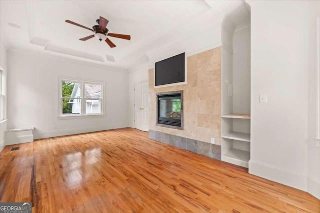 6771 Sunny Brook Ln, Atlanta, GA 30328 - unfurnished living room with wood finished floors, crown molding, a tray ceiling, a ceiling fan, and a tiled fireplace