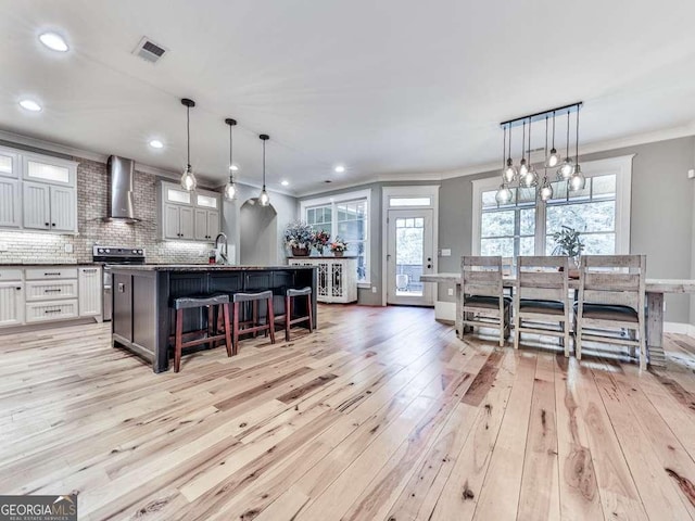 4454 Damascus Rd, Jasper, GA 30143 - kitchen with wall chimney range hood, light wood-style floors, stainless steel stove, ornamental molding, and a kitchen breakfast bar