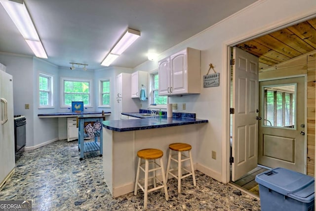 4618 Jones Gap Rd, Hiawassee, GA 30546 - kitchen with white cabinets, baseboards, a kitchen breakfast bar, and dark countertops