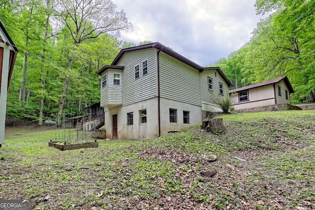 4618 Jones Gap Rd, Hiawassee, GA 30546 - back of house with a vegetable garden, stucco siding, stairs, and a view of trees