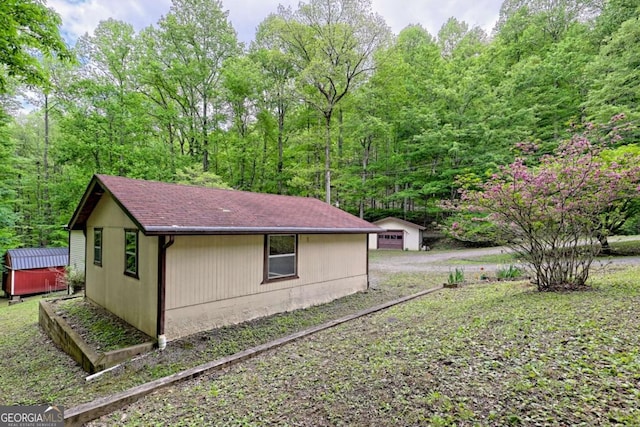 4618 Jones Gap Rd, Hiawassee, GA 30546 - view of home's exterior featuring an outbuilding, a shingled roof, and a wooded view