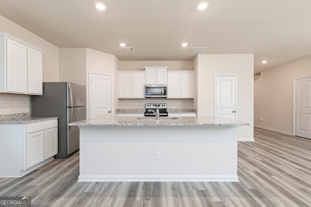 295 Limestone Cir, Conyers, GA 30013 - kitchen featuring appliances with stainless steel finishes, a sink, a kitchen island with sink, light wood-type flooring, and white cabinets