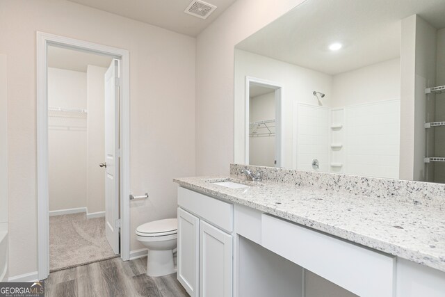 295 Limestone Cir, Conyers, GA 30013 - bathroom featuring vanity, wood finished floors, toilet, a spacious closet, and a shower