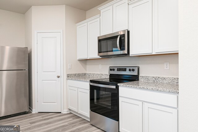 295 Limestone Cir, Conyers, GA 30013 - kitchen with stainless steel appliances, light wood-style flooring, white cabinets, and light stone counters