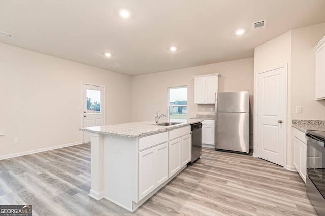 295 Limestone Cir, Conyers, GA 30013 - kitchen with appliances with stainless steel finishes, a sink, white cabinets, a center island with sink, and light wood-style floors