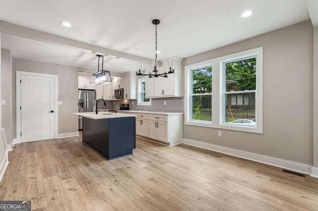 1283 Beecher St SW, Atlanta, GA 30310 - kitchen with appliances with stainless steel finishes, light countertops, light wood finished floors, white cabinets, and tasteful backsplash